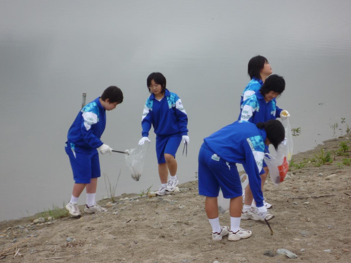海岸に捨てられた空き缶や空き瓶などのゴミを拾う児童