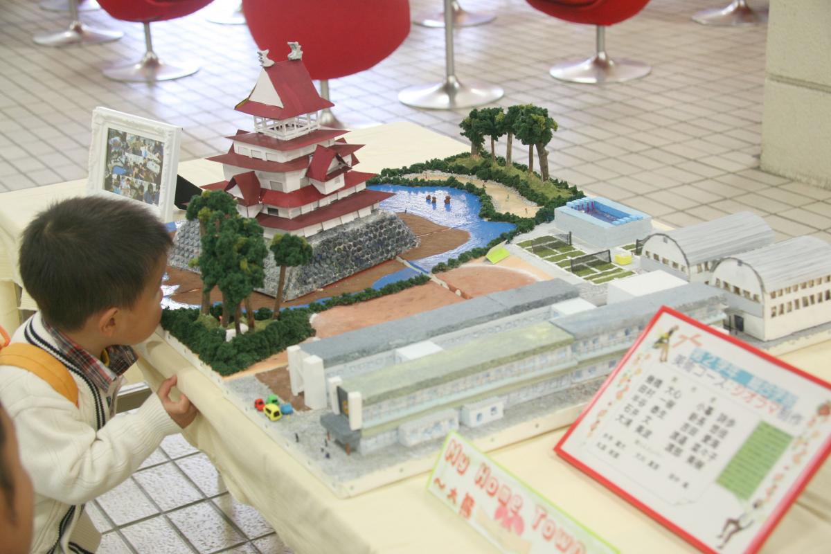 生徒が制作した鶴ヶ城のジオラマ作品を興味深く見つめる男の子