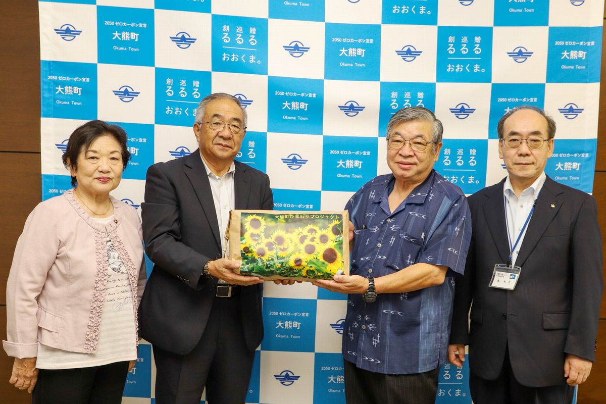 鈴木副理事長（右から2人目）に種を手渡す渡部会長（右から3人目）