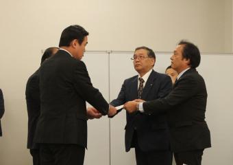 小里副大臣に申し入れ書を手渡す渡辺町長と伊澤町長の写真