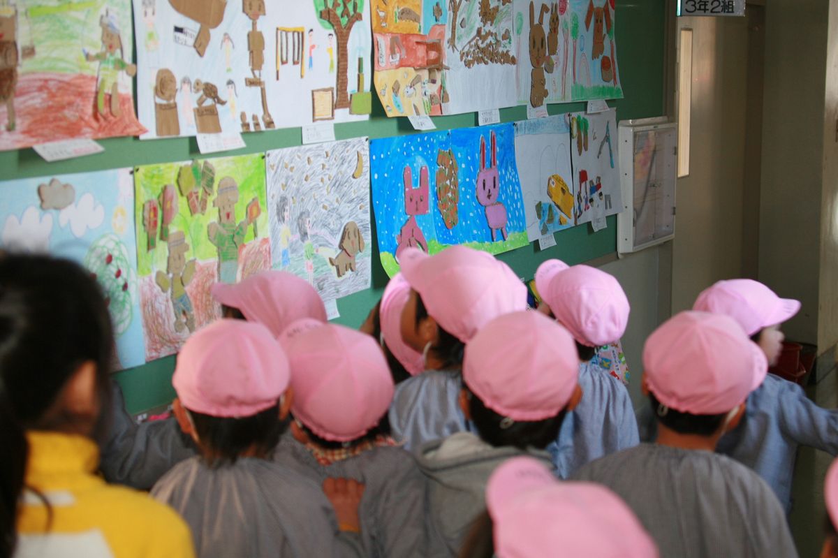 廊下に貼り出された小学生の「切り絵」作品を興味深く見つめる園児たち
