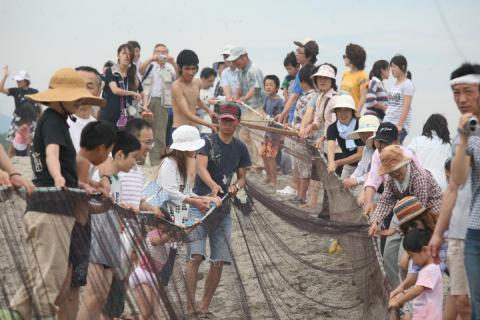 毎年恒例の地引き網では集まった海水浴客たちによって力いっぱい網が引かれました。魚が見えるたびに歓声を上げていました。