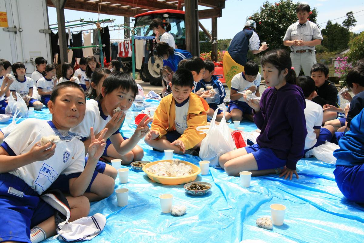 田植えのあと熊町地区の方のご厚意で準備されたおにぎりを食べる児童たち