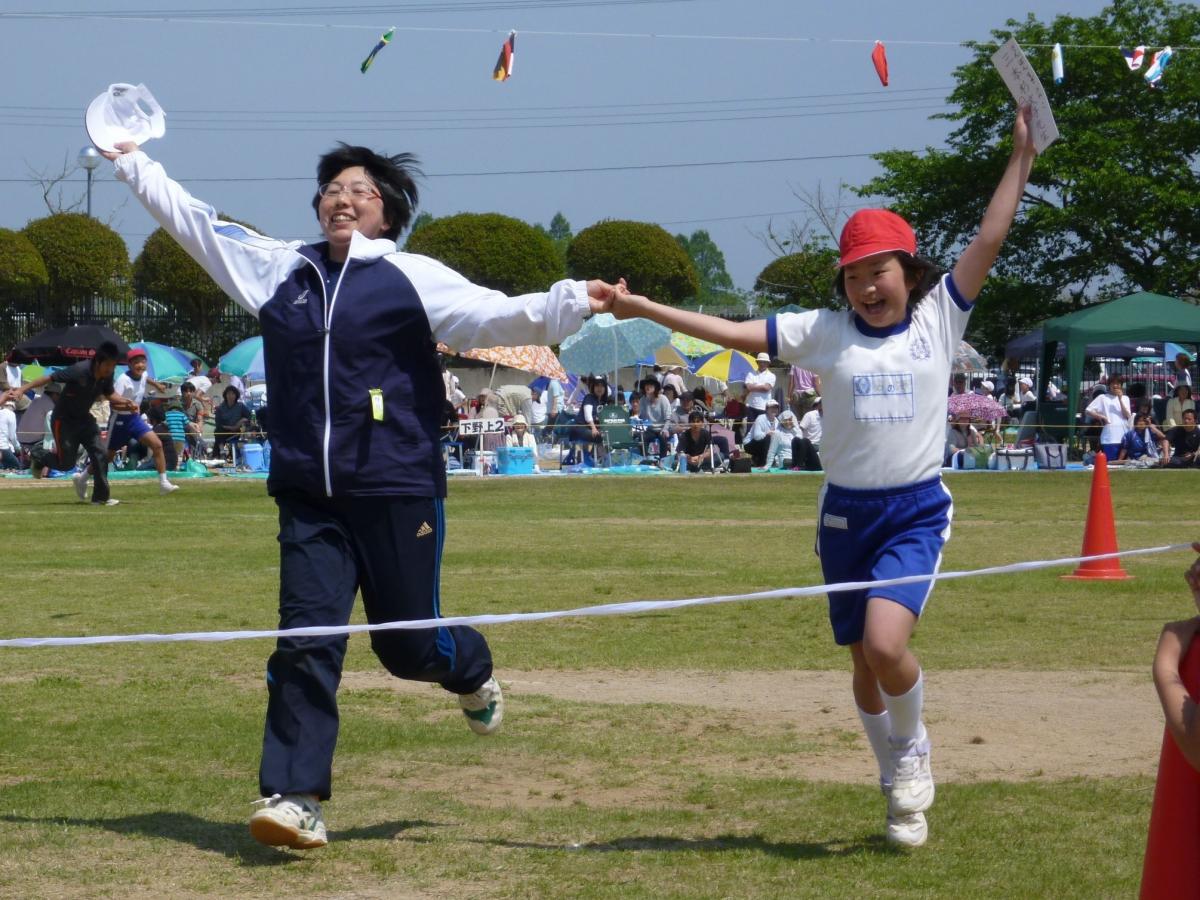 手をつなぎガッツポーズでゴールする6年生と先生