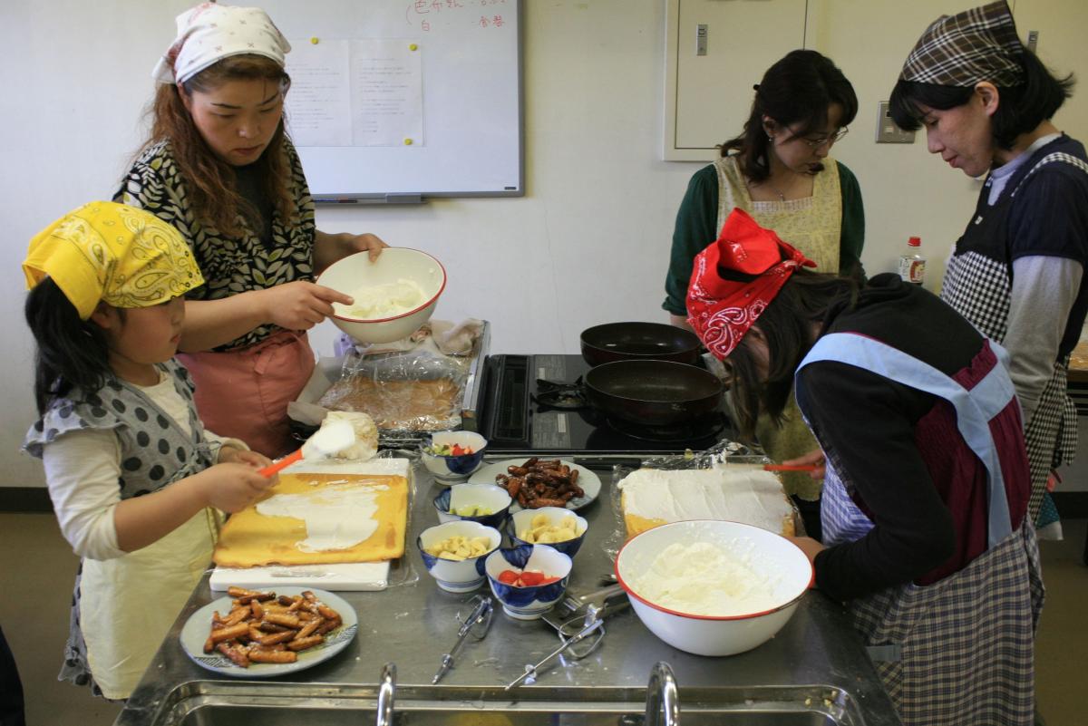 生地が焼き上がり、スポンジにクリームを塗る親子