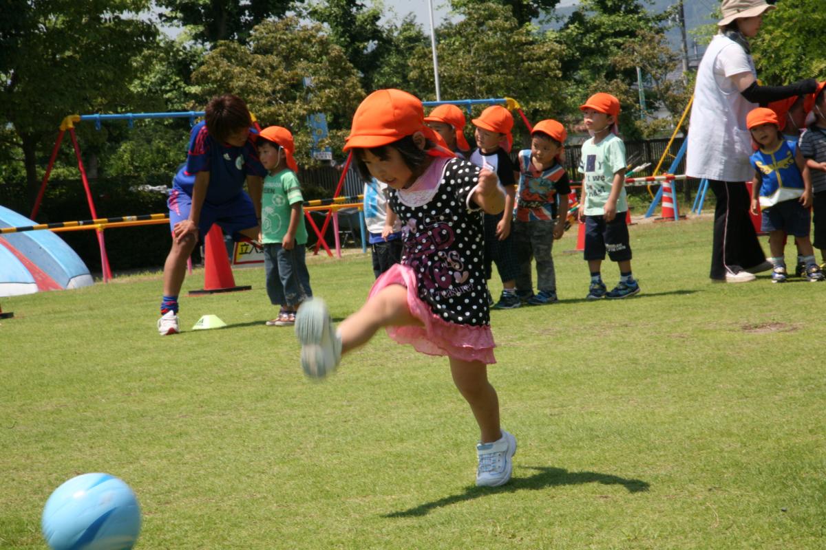 上手なキックでサッカーボールを飛ばす園児