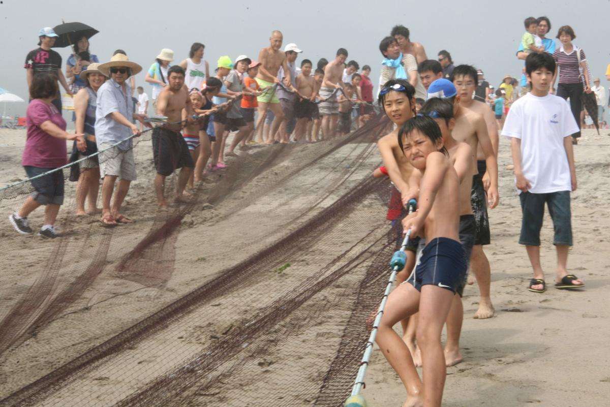 恒例の地引き網を力いっぱいに引く海水浴客