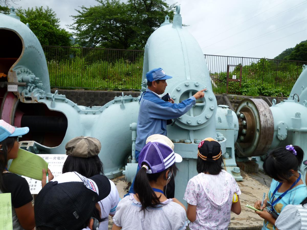 大正時代に実際に使われていた水車発電機を見学する子どもたち