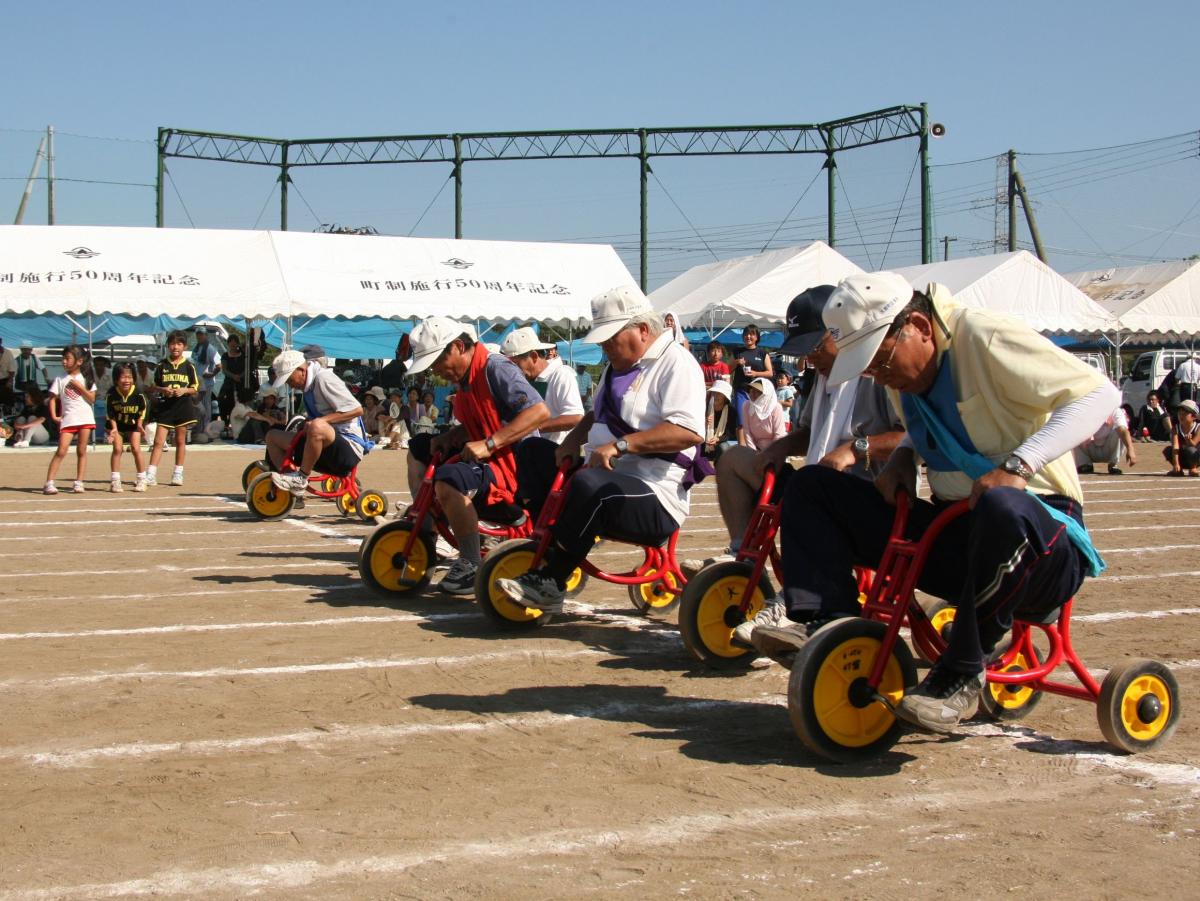 「鉄人リレー」スタートの合図で一斉に三輪車を漕ぐ町民