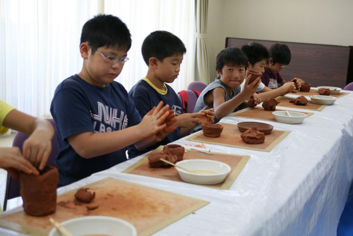 真剣な表情で土器の形を整える子どもたち