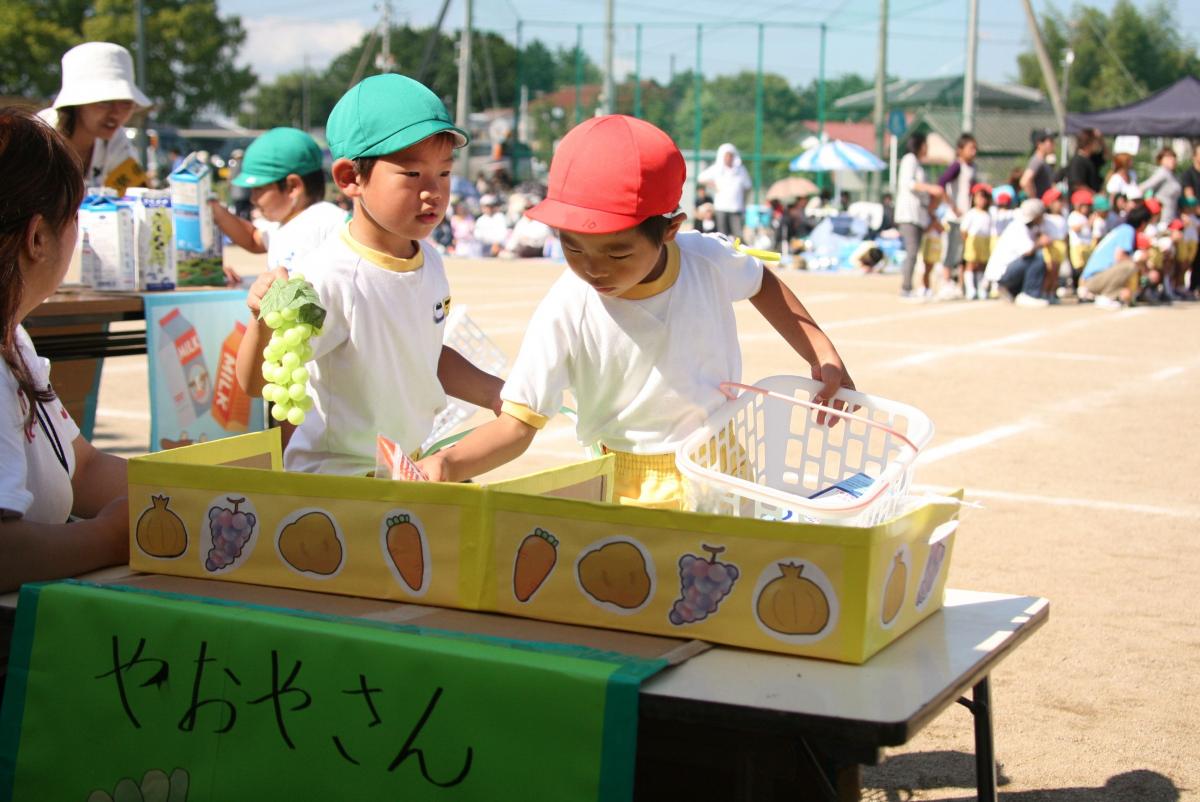 お買いもの競争で野菜や果物をかごに入れる園児