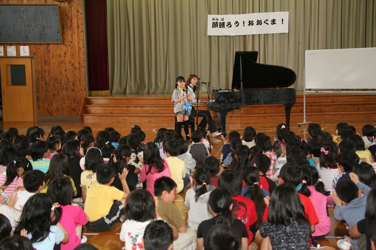 堀さんの演奏で歌を歌う児童と、拍手で盛り上がる熊町・大野小の児童たち