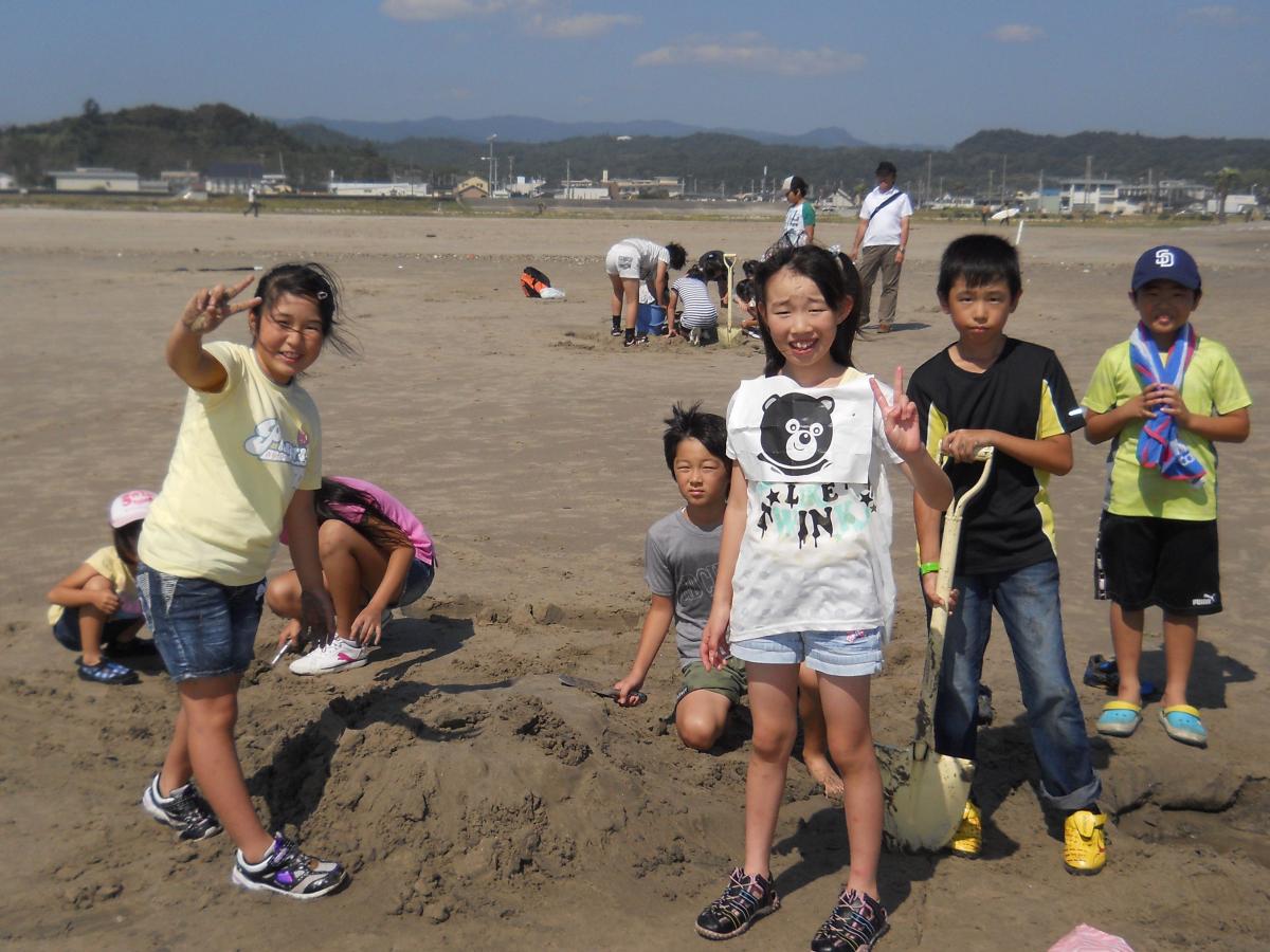 協力して砂の芸術を作る参加児童たち