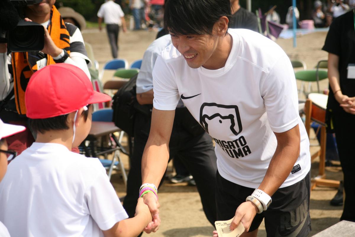特別参加の大熊町出身・秋本真吾さんと握手をする児童