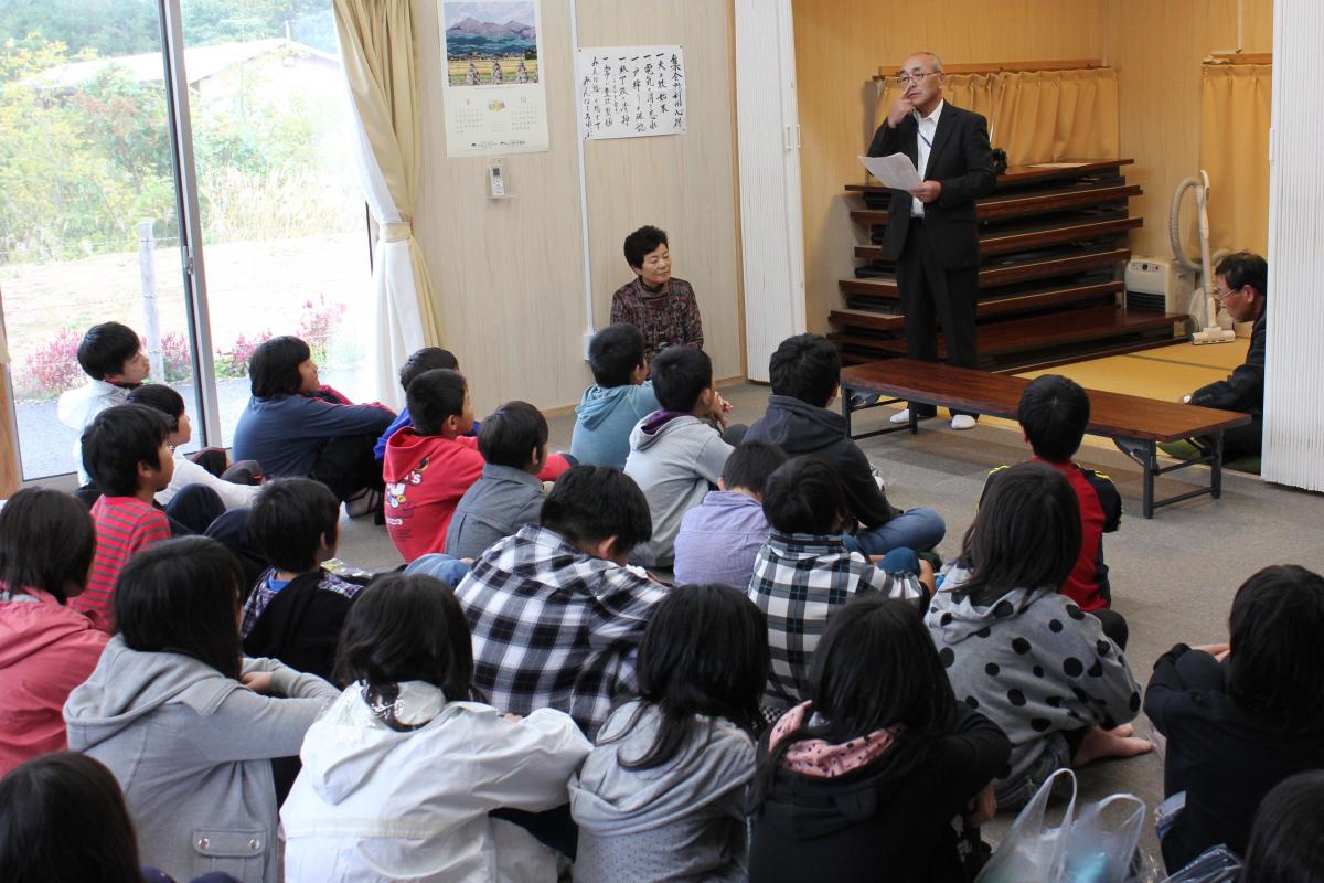 集会所で行われたふれあいタイムで自治会長から大熊町民の避難の現状の話をされ、聞き入る子どもたち（2）