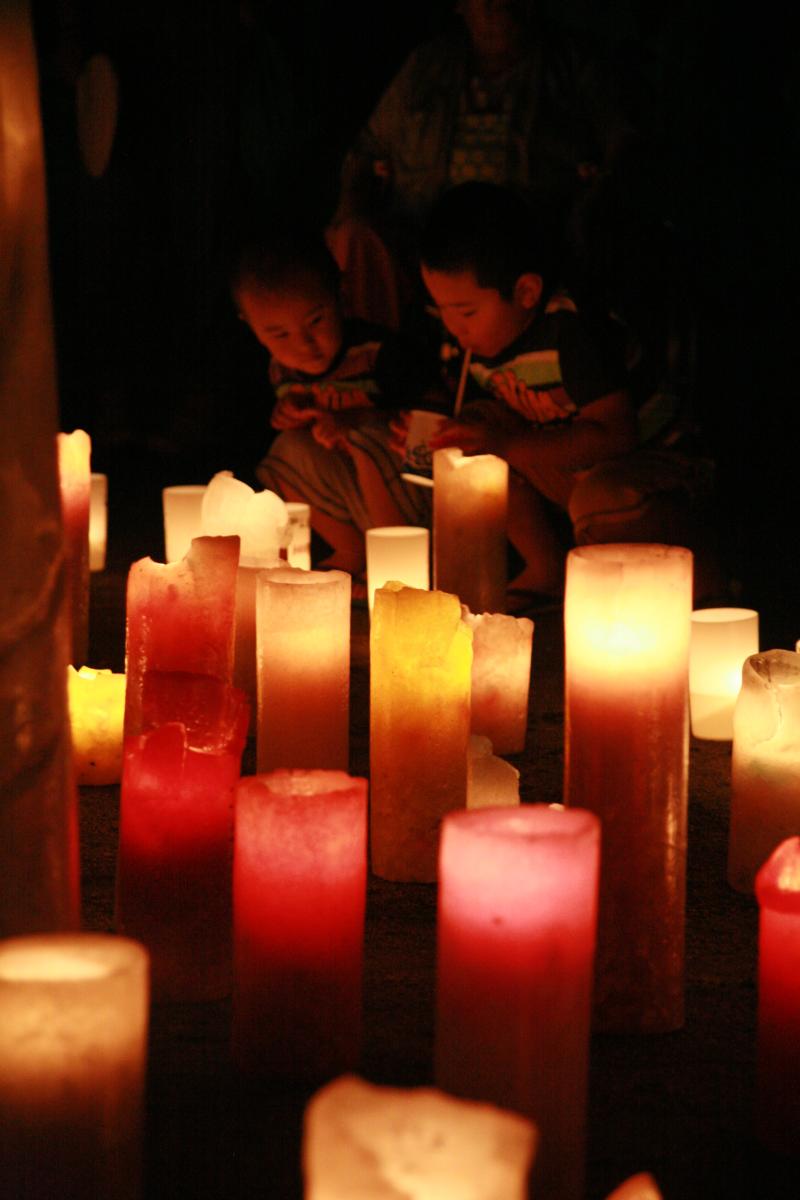 夏の夜をほのかに照らすたくさんのキャンドルを見つめる子どもたち