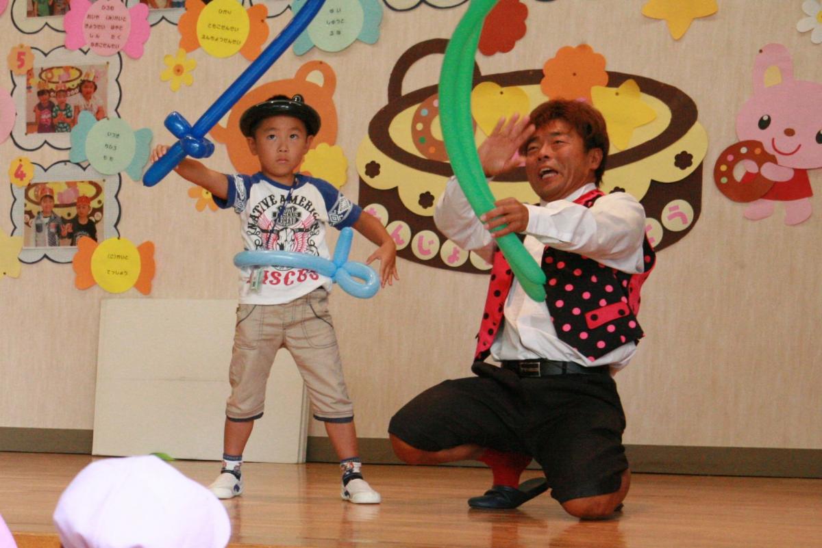 風船で作った剣とベルトを付け凛々しい顔でポーズを決める園児