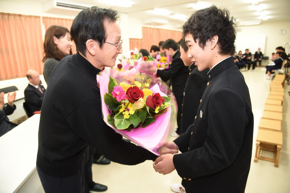 支援者の方に感謝の花束を手渡し、握手を交わす生徒