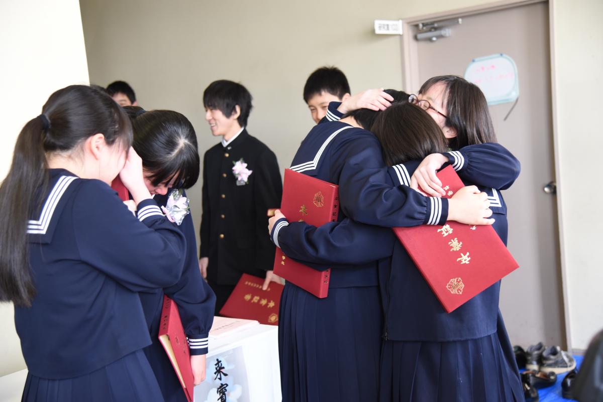 式場を出た後、抱き合って別れを惜しむ卒業生たち