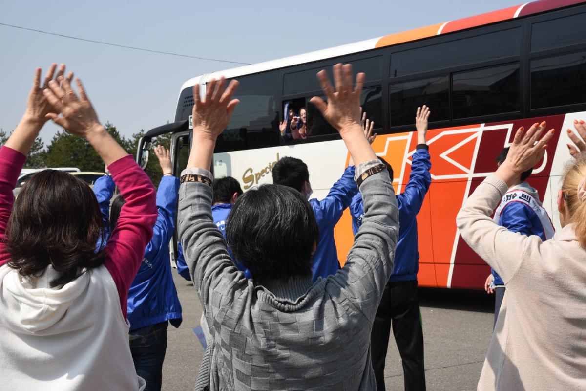 お別れのとき。中学生が乗り込んだバスに、大きく手を振る仮設住民