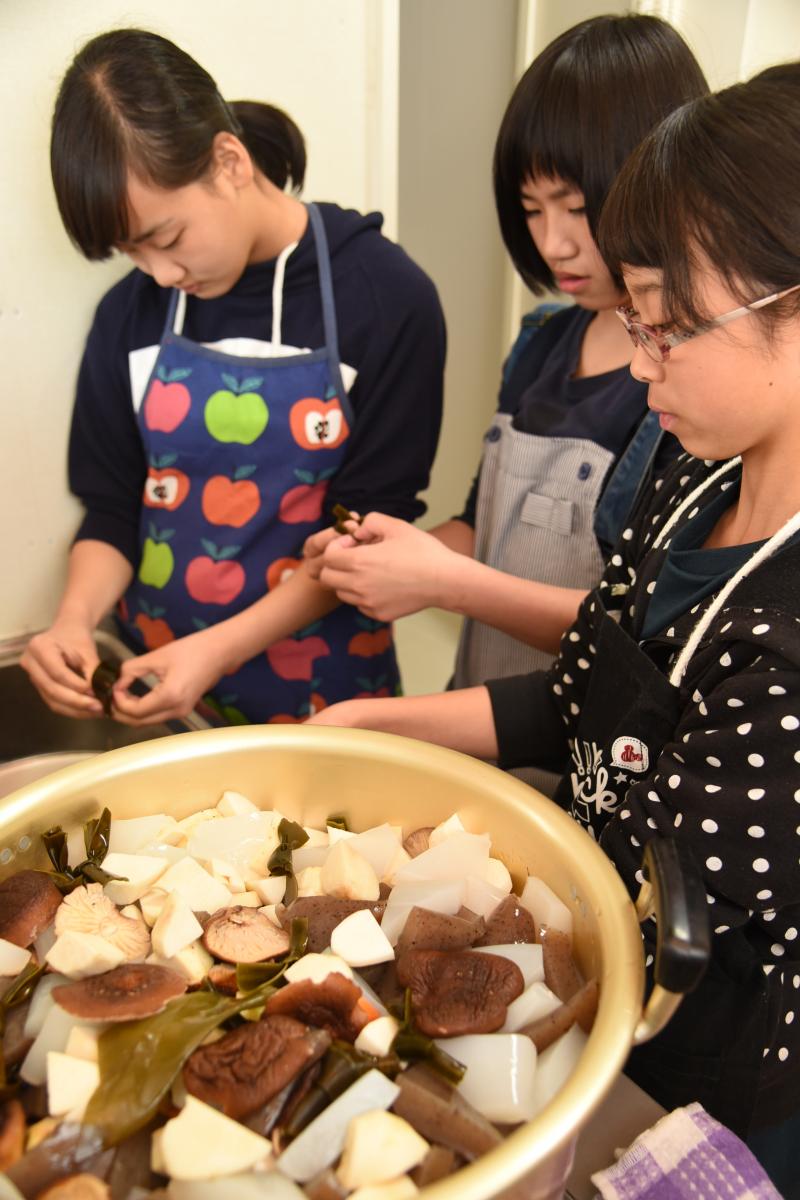 鍋に入れる昆布を結ぶ中学生