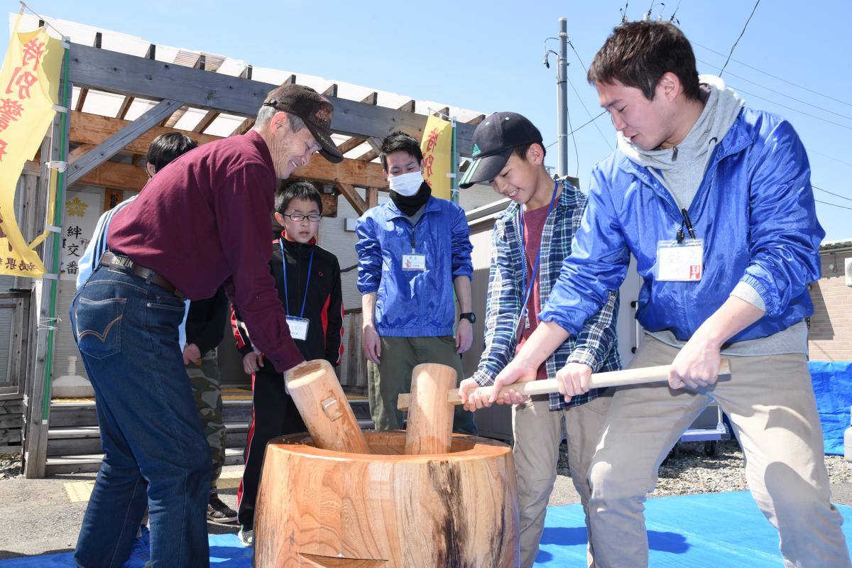 笑顔で餅つきをする参加中学生と町民