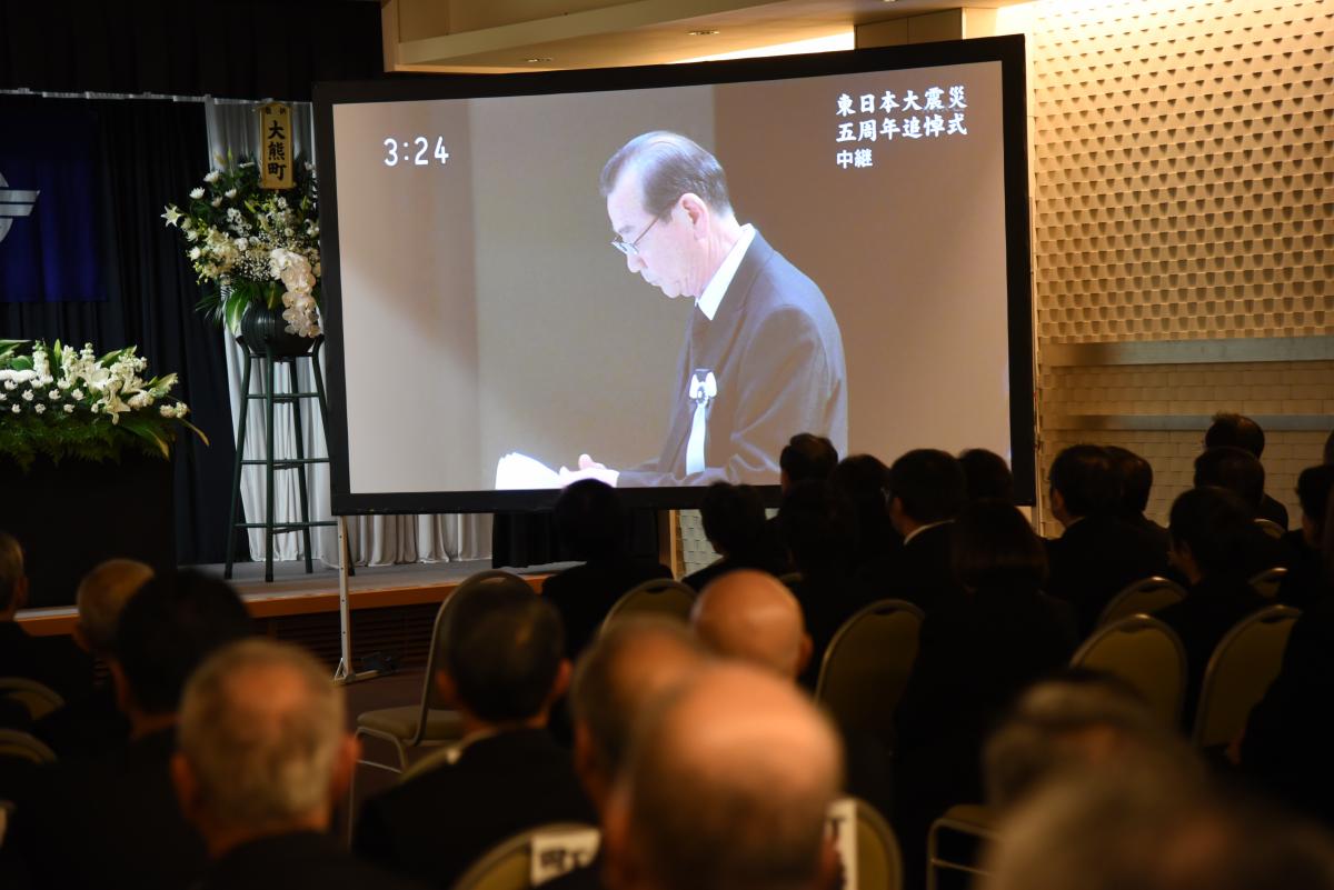 政府主催の追悼式の中継映像で、県代表の佐久間さんの言葉に耳を傾ける参列者