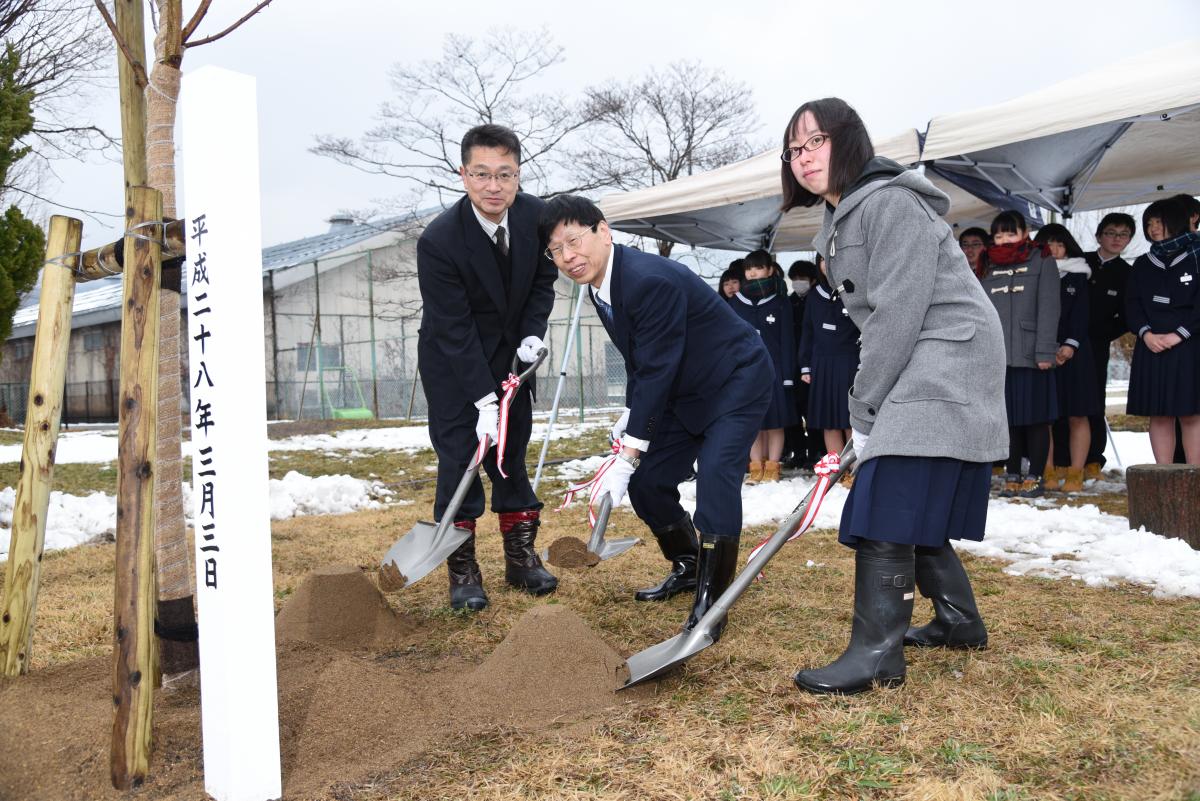 さくらの苗木に土をかぶせる会津短大理事長、大熊中校長、生徒代表