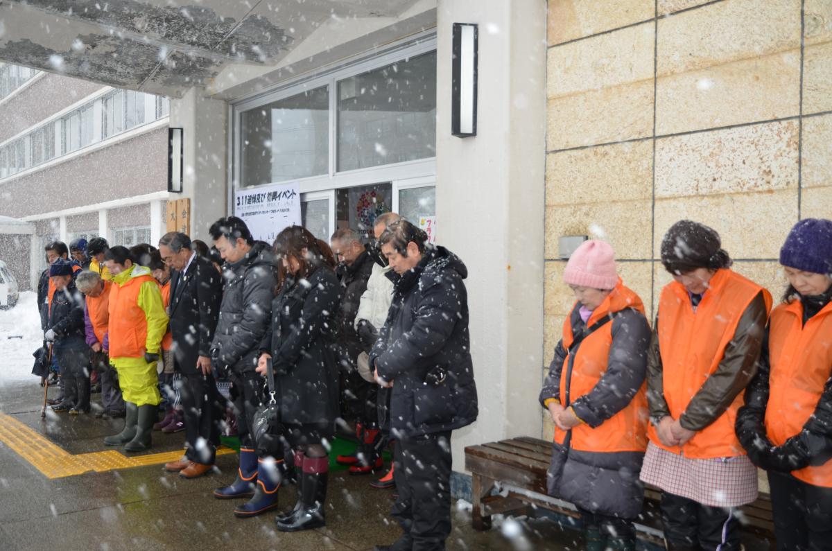 降りしきる雪の中、黙とうを捧げる参加者