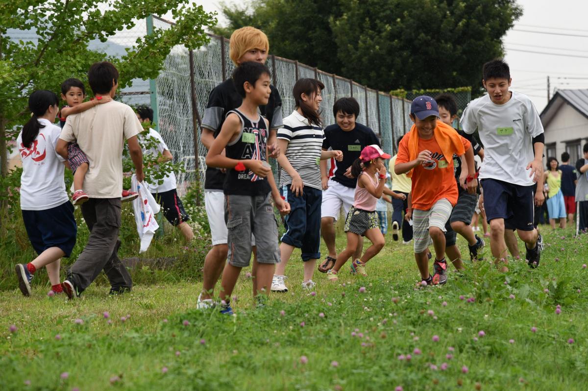 ボランティアの学生と楽しそうに走り回る児童たち