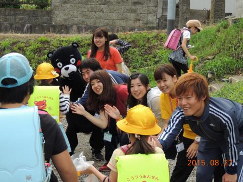 登校する熊町・大野小学校の児童にハイタッチであいさつする大学生たち