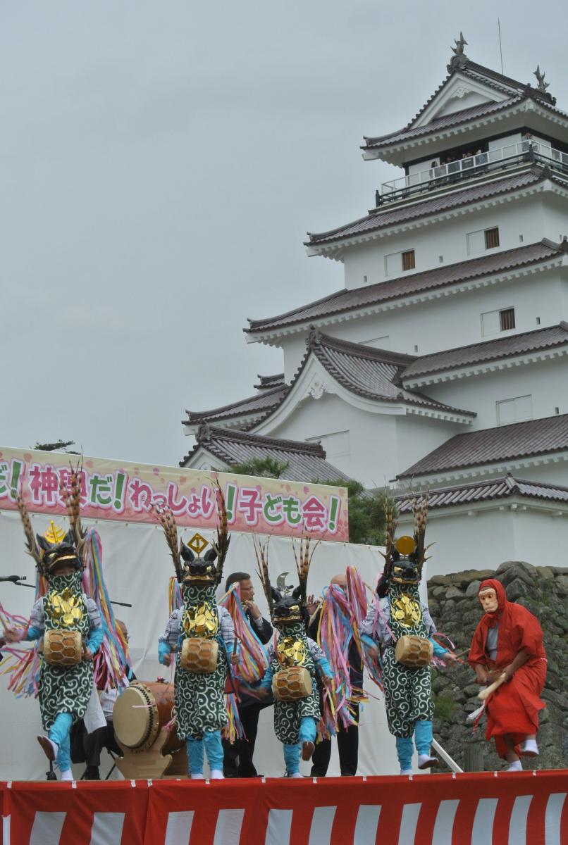 鶴ヶ城天守閣をバックに伝統の舞を見事に披露するメンバー
