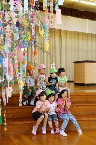 体育館に飾られた大きな笹の木の下でポーズを決める園児たち