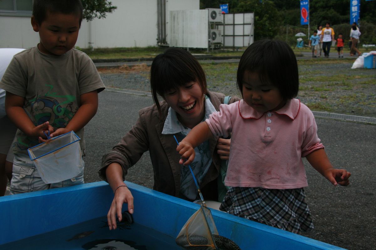 疑似体験コーナーで小さな網で魚をすくう女の子