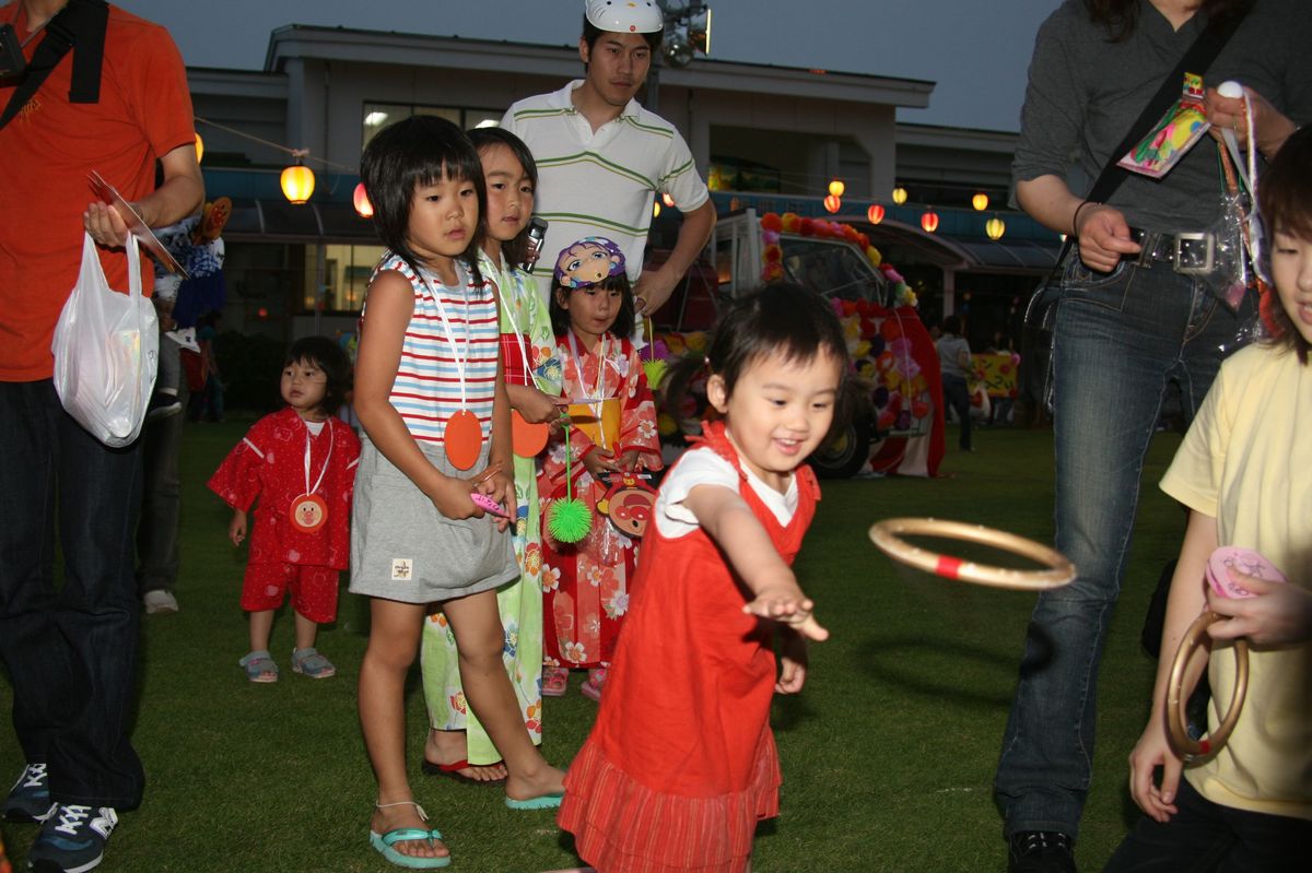 ニコニコで輪投げをする女の子とそれを見守る他の子どもたち