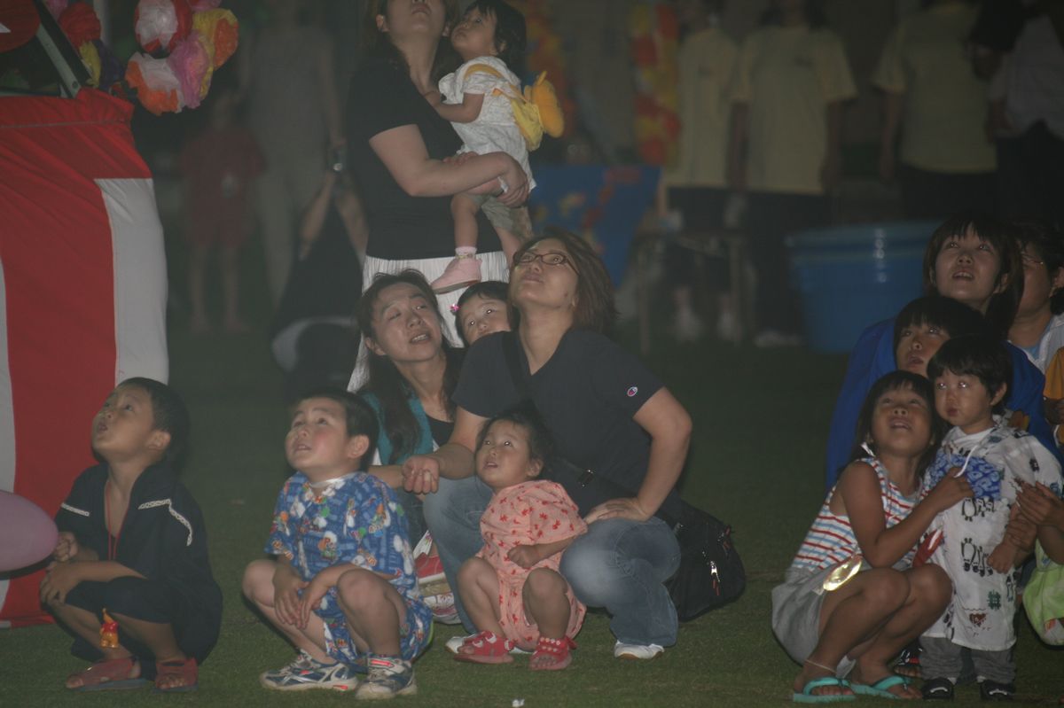 祭りの最後に行われた花火大会で空に咲く花火を見上げる子どもたちと保護者の方（2）