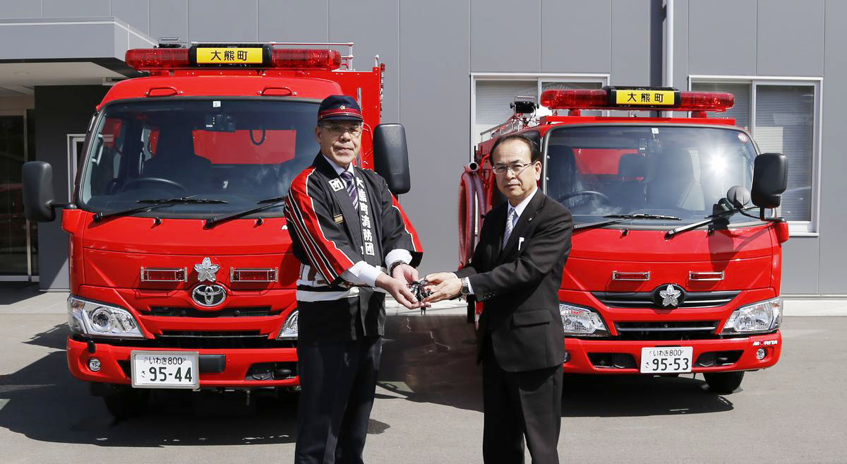 町長から消防車の鍵を受け取る団長（左）