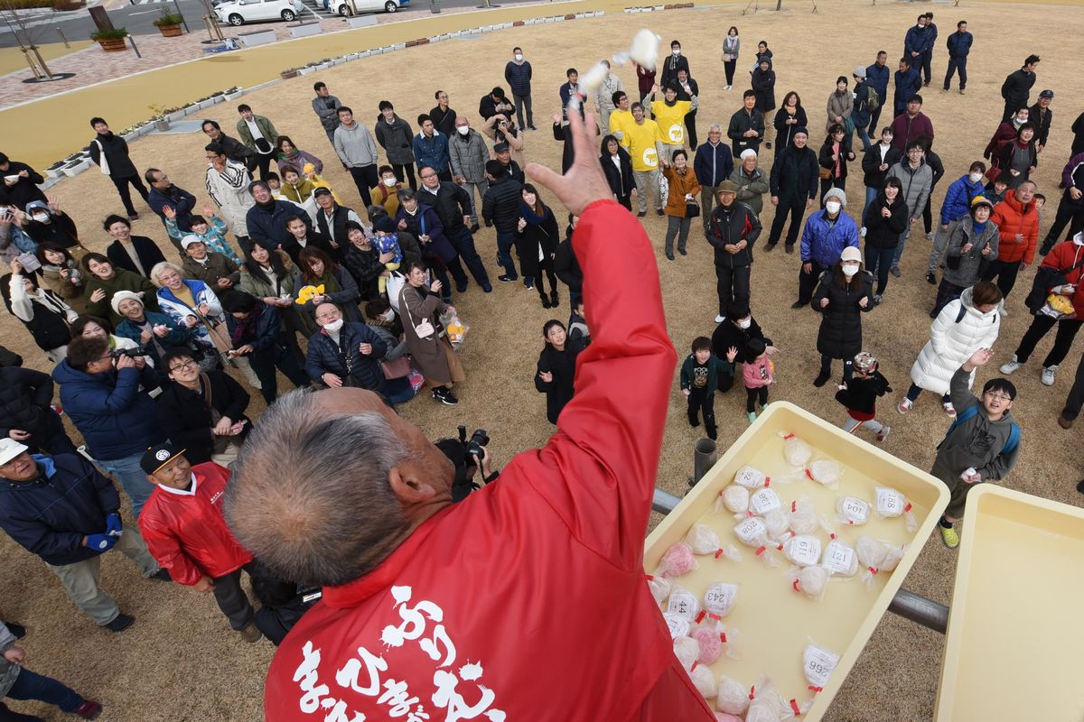 特設のやぐらから紅白のもちをまく実行委員会