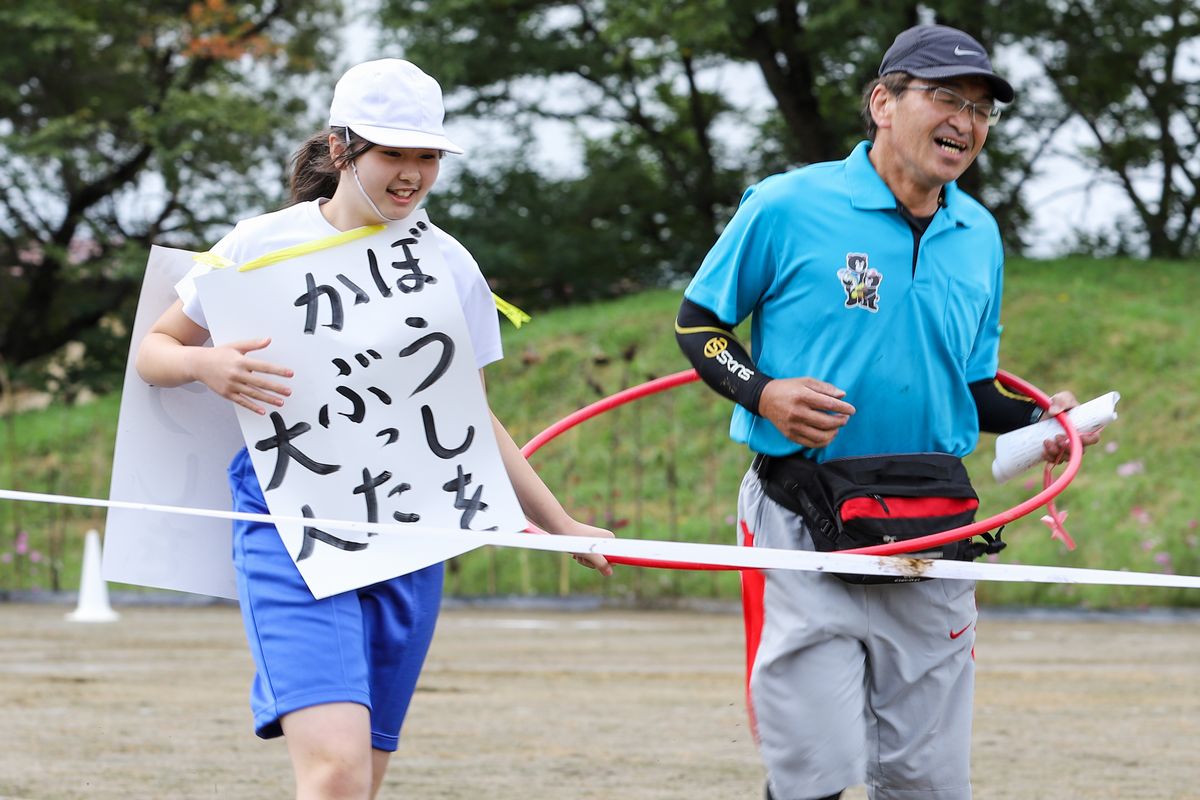 帽子をかぶった大人を見つけ、ゴールめがけて走る児童