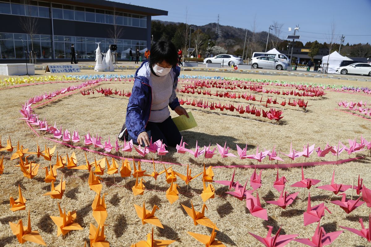 ピンクの折り鶴でハート型を飾り付ける町民
