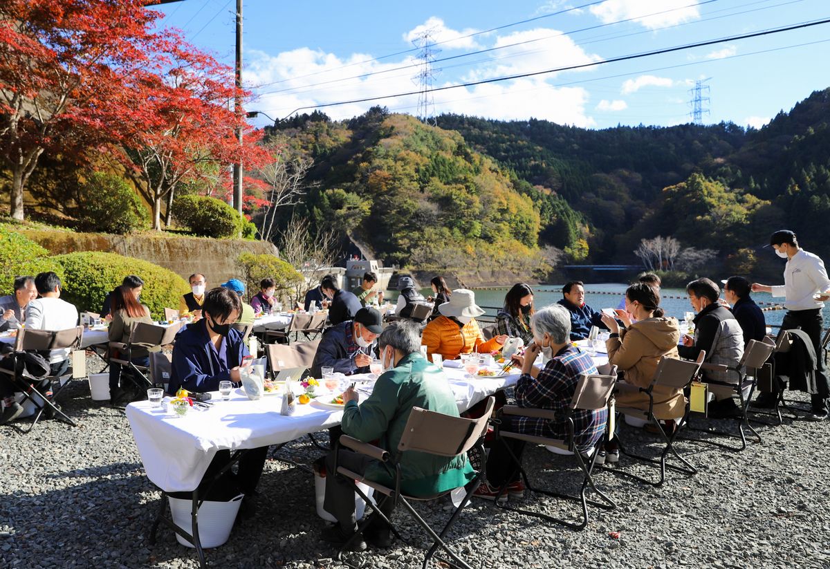 坂下ダム湖畔に特設された屋外レストランで料理を味わう参加者