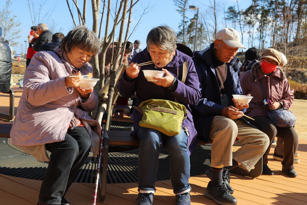 振る舞われたもちを味わう参加者