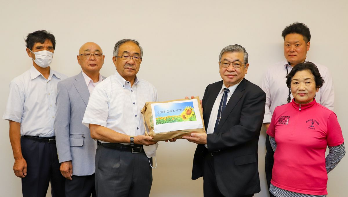 鈴木副理事長（右から3人目）に種を手渡す渡部会長（左から3人目）