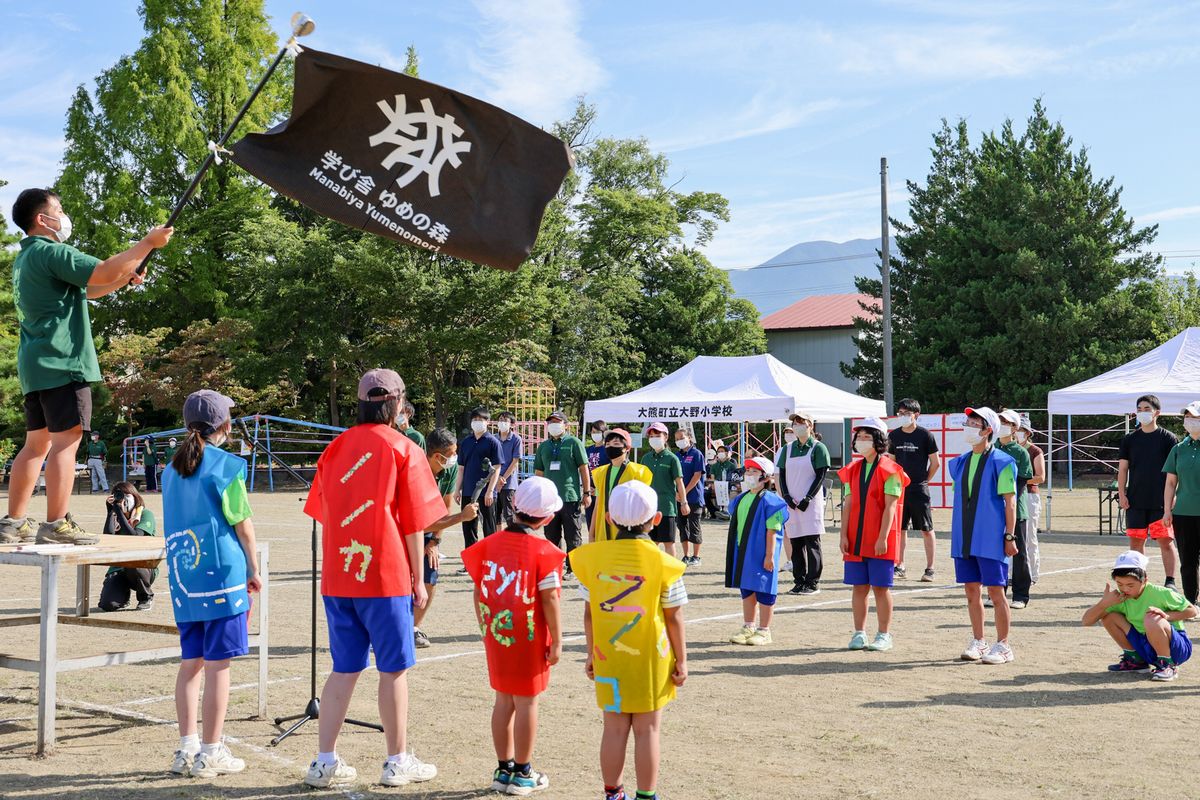 「学び舎ゆめの森のうた」を斉唱する児童生徒。歌に乗せて校旗がはためいています。