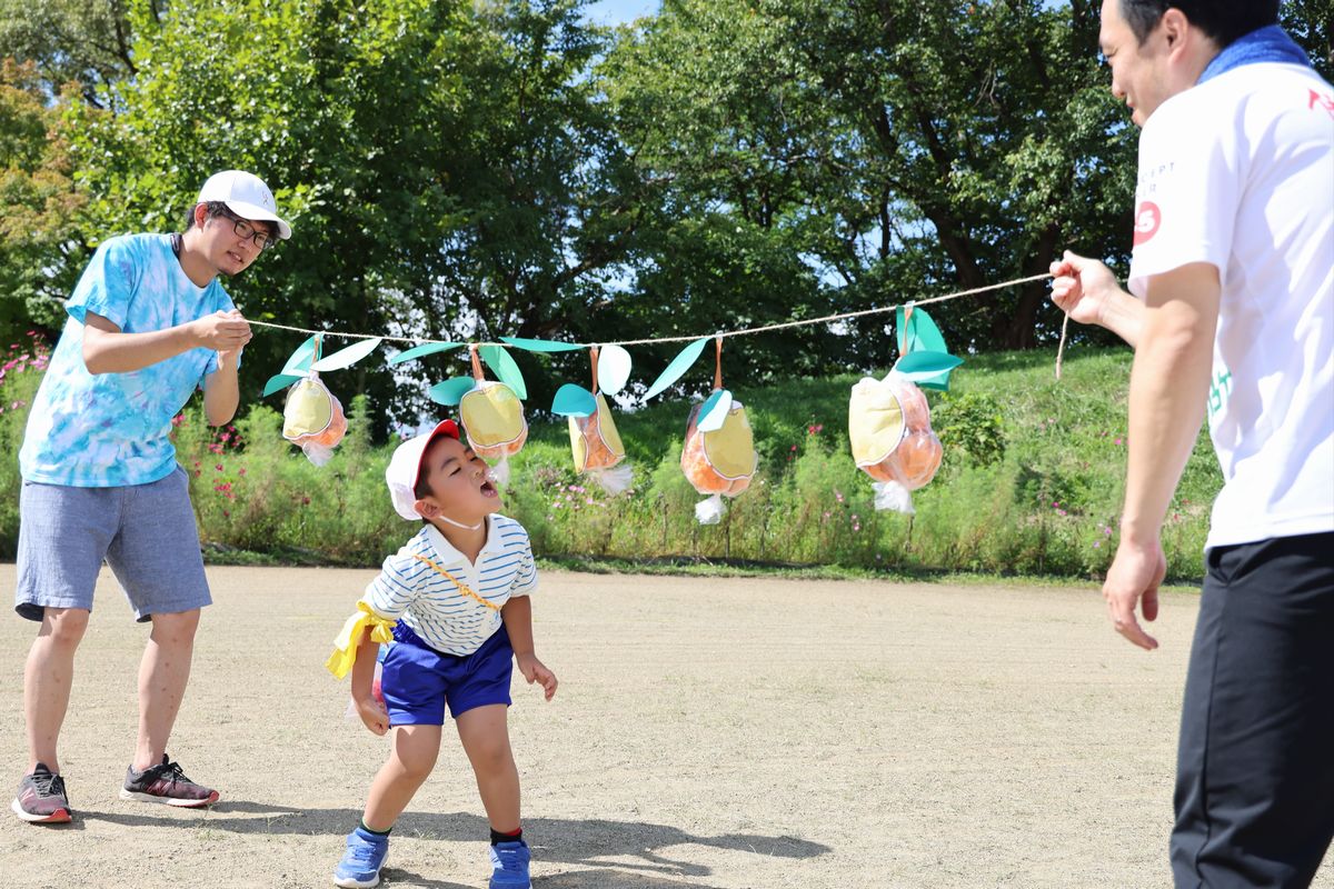 大熊町のおいしい物をゲットしよう！園児はいちごを拾った後、震災前、町の特産品だった梨の実を口でもぎ取り、続いて三角コーンの中に隠されたキウイジュース（はずれあり）を探しゴールを目指しました。