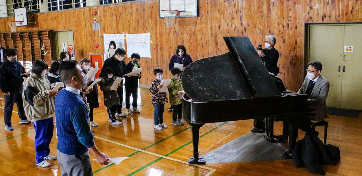 関口さん（右）から発声方法を教わる子どもたち