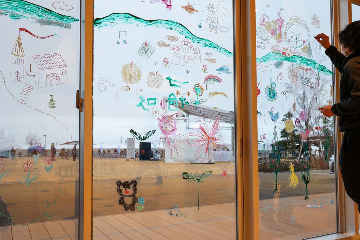 本庁舎おおくまホール内の大きなガラス窓に「2050年、ぼくらが大熊町で暮らすなら」をテーマに、学び舎ゆめの森の児童生徒や来場者が参加して「2050年の大熊町」を想像してもらいみんなでひとつの町を描きました。