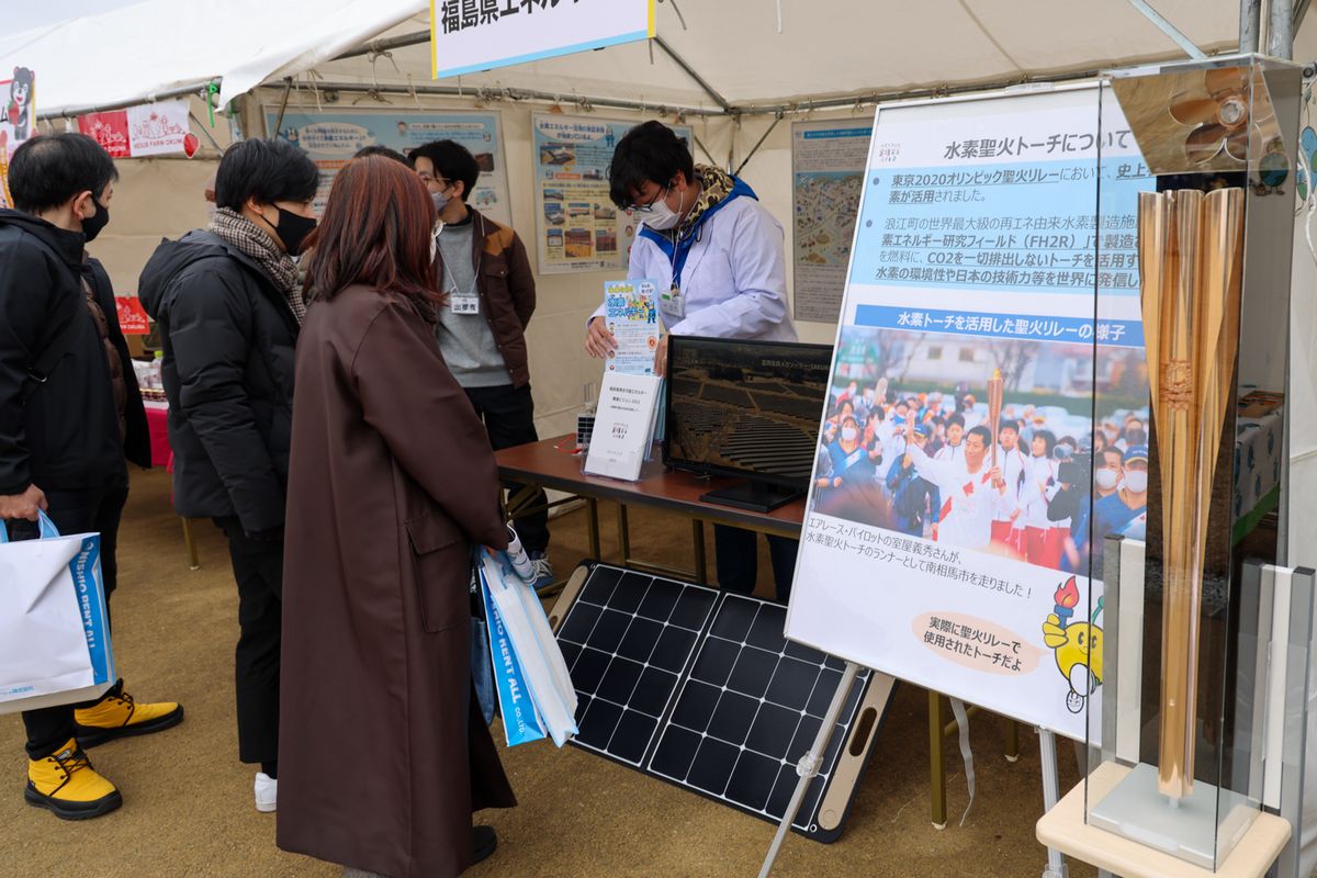 福島県エネルギー課のブースでは、トーチ展示（写真右端）や燃料電池の仕組みデモ・説明が行われました。