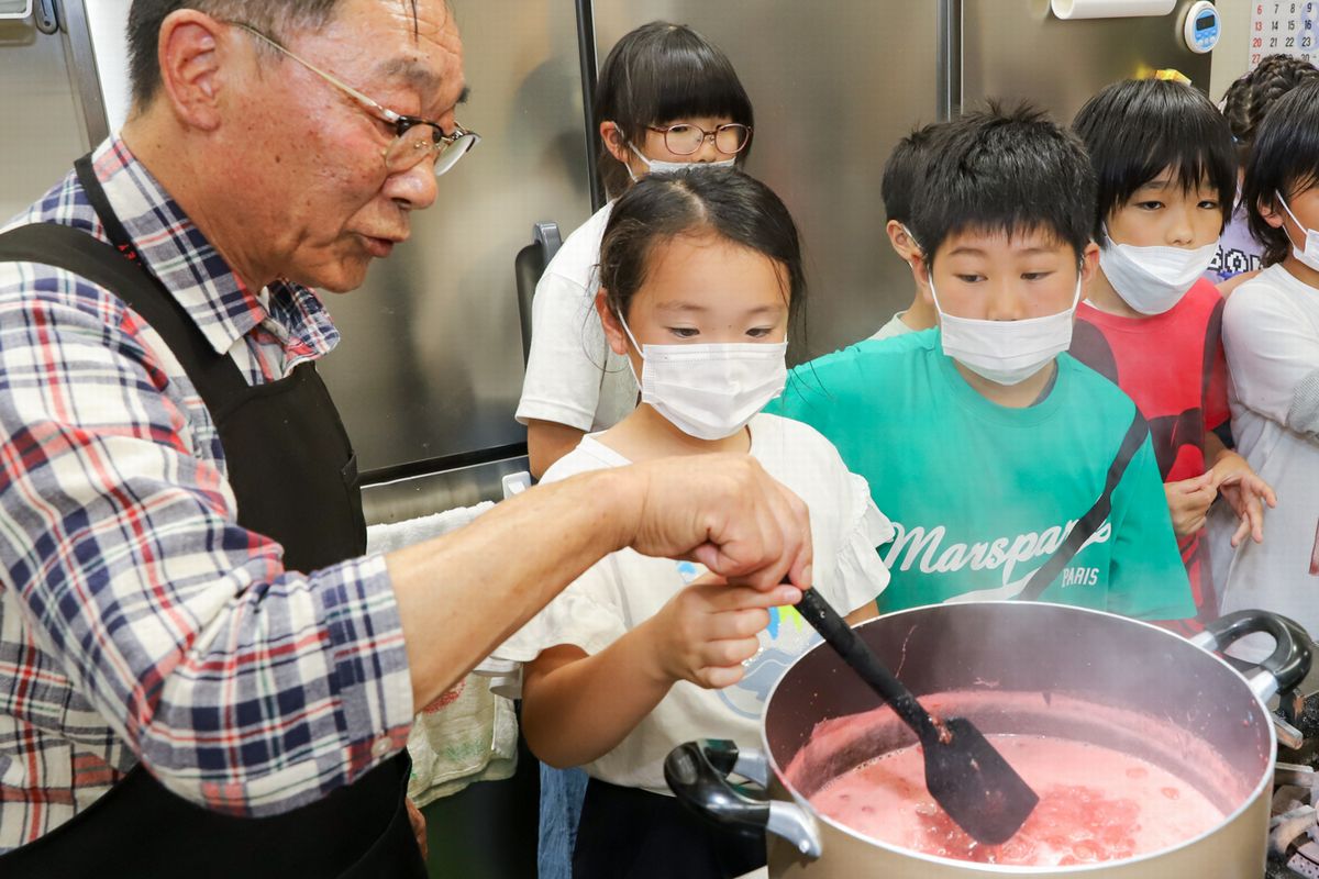 鍋が沸騰しピンク色のアクが出ています。マスターの武内さんはマッシャーからヘラに持ち替え焦げないようにかき混ぜます。説明の後は、子どもたちが順番で実践です。