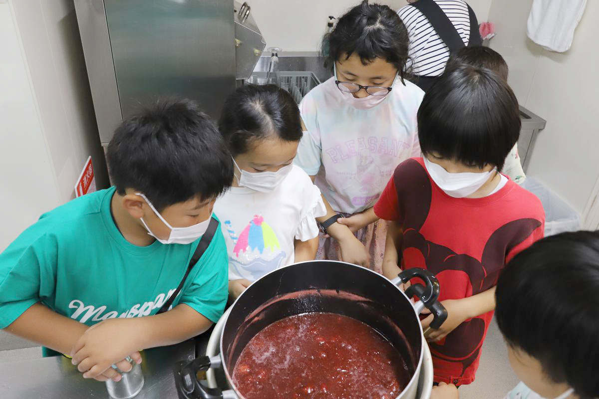 煮詰められたイチゴの鍋は、火からおろされ粗熱を取るため冷水の入った一回り大きな鍋に入れられました。アクが消え子どもたちは出来上がった鍋をじっと覗き込んでいます。